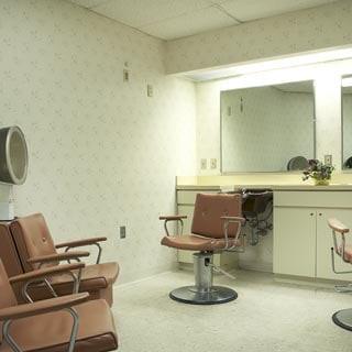 An empty salon with vintage chairs facing a large mirror.