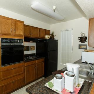 A modern kitchen with wooden cabinets, a black refrigerator, and built-in oven.