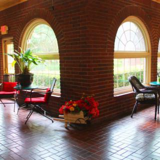 A cozy indoor seating area with brick walls, arched windows, and plants.