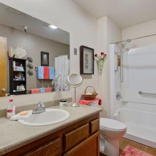 A well-organized bathroom with a large mirror, sink, and shower area.