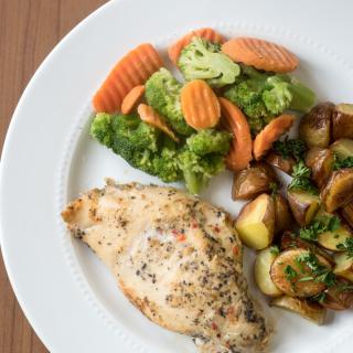 A delicious plate featuring grilled chicken, roasted potatoes, and mixed vegetables.