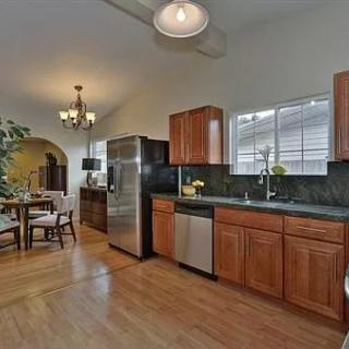 A modern kitchen with wooden cabinets, stainless steel appliances, and a dining area.