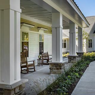 A serene porch with rocking chairs and white columns overlooking a landscaped garden.