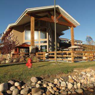 A modern house with a unique architectural design, surrounded by a landscaped yard and rocks.