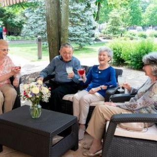A group of seniors enjoying a social gathering outdoors with drinks in hand.