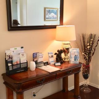 A cozy entryway showcasing a wooden table with decorative items, a lamp, and a mirror.