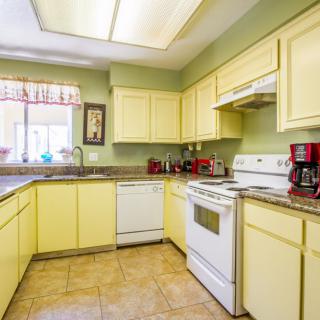 A bright kitchen with yellow cabinets and modern appliances.