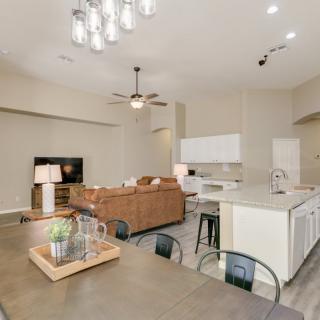 A modern open-concept living space featuring a kitchen, dining area, and comfortable living room with neutral tones.