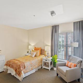 A cozy and modern bedroom with a single bed, armchair, and ample natural light.