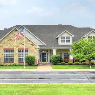 A suburban brick house with a well-maintained lawn and an American flag displayed.