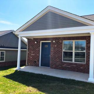 A brick house with a front porch under a clear blue sky.