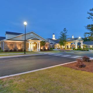 A well-lit building at dusk with an inviting driveway.