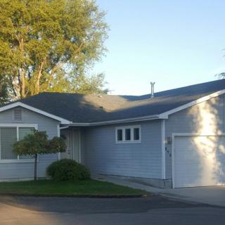 A suburban house with a driveway and trees in the front yard.