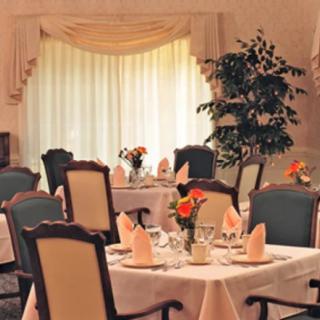 An elegant restaurant dining room set with neatly arranged tables and chairs, adorned with floral centerpieces and folded napkins.