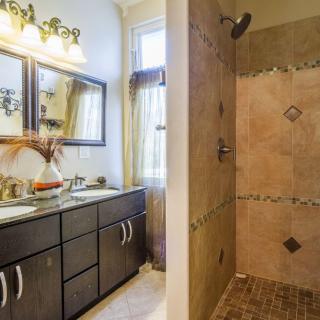 A modern bathroom featuring a double sink vanity and a tiled walk-in shower.
