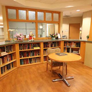 A cozy reading area featuring bookshelves filled with various books, accompanied by a wooden table and chairs.