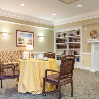 A cozy interior room with a table and chairs, a bookshelf, and a fireplace.