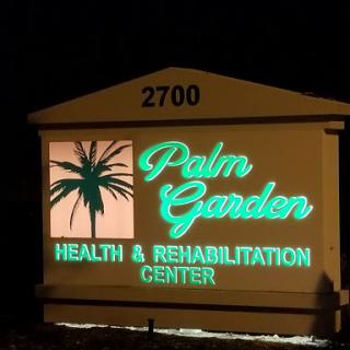 Illuminated sign for Palm Garden Health & Rehabilitation Center at night.