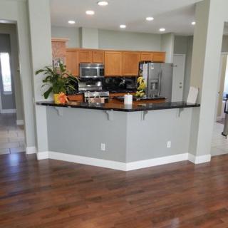 A modern kitchen with wood flooring and stainless steel appliances.