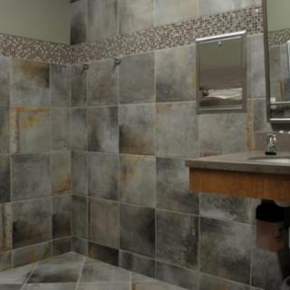 A modern bathroom featuring a tiled shower, sink, and mirror.