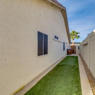 A side yard featuring artificial turf alongside the exterior wall of a house, bordered by a fence.