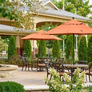 A tranquil outdoor patio area with tables and orange umbrellas, surrounded by lush greenery.