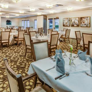 An elegant dining room with neatly arranged tables and chairs, featuring soft lighting and decorative elements.