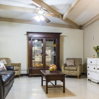 A cozy living room with a sofa, armchairs, and a wooden cabinet.