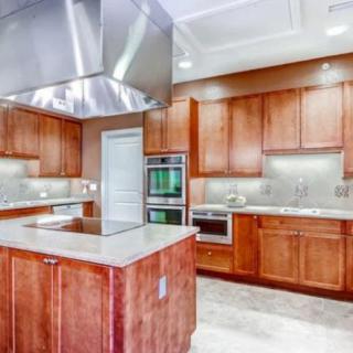 A modern kitchen with wood cabinets, stainless steel appliances, and a central island.