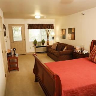 A cozy bedroom with a large bed, sofa, and warm lighting.