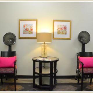 A cozy salon waiting area with chairs, hair dryers, and warm lighting.