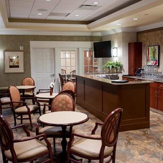 A cozy cafe interior with round tables and cushioned chairs, featuring warm lighting and elegant decor.