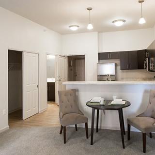 A modern apartment interior featuring a small dining area and a kitchen with minimalist design.