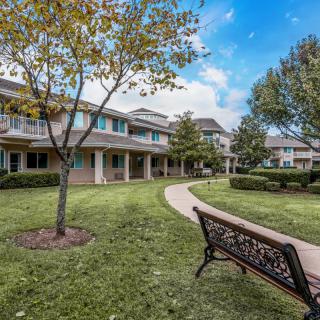 A peaceful outdoor area with a walkway, surrounded by trees and residential buildings.