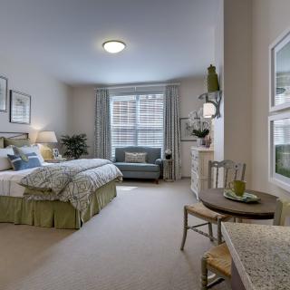 A cozy and well-decorated bedroom with a bed, seating area, and soft lighting.