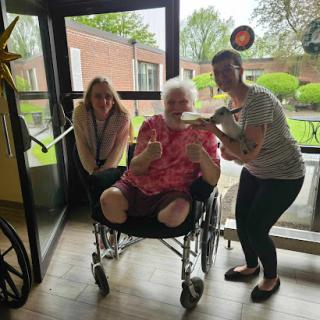 A joyful moment with caregivers and an elderly individual in a cheerful indoor setting.