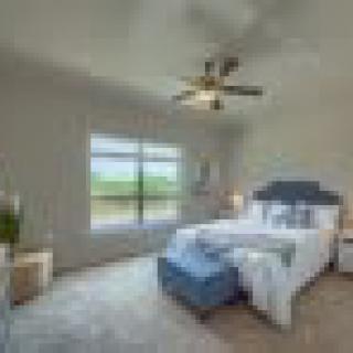 A modern bedroom with a large window, stylish decor, and a ceiling fan.