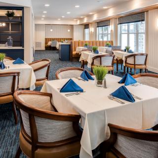 Elegant restaurant dining area with tables set for guests, featuring blue napkins and modern decor.