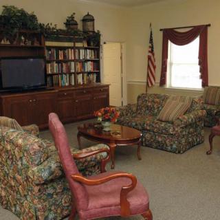 A cozy living room with patterned sofas and armchairs, a TV, and a bookshelf.