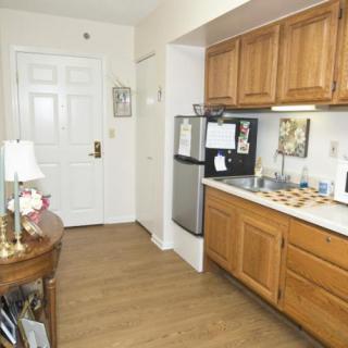 A cozy apartment kitchen with wooden cabinets and a small fridge.