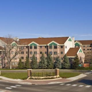 A suburban residential building with a manicured landscape and a clear blue sky.