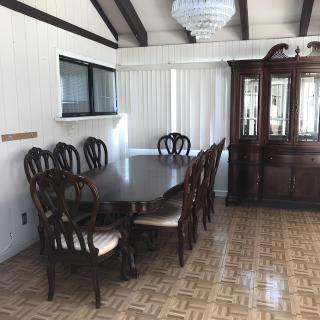 A dining room featuring a large wooden table with chairs, a chandelier, and a cabinet.
