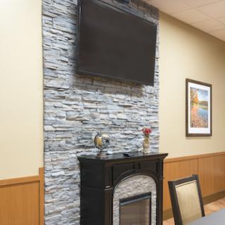 A stylish interior featuring a stone wall, a modern fireplace, and a television above it.