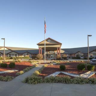 A well-maintained building exterior with a flagpole and landscaped garden under a clear sky.