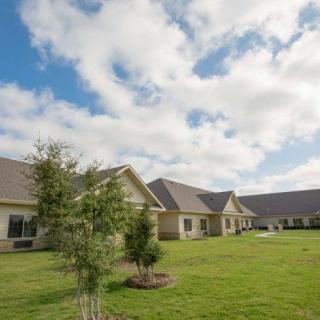 A suburban scene featuring several houses with neatly maintained lawns and trees under a partly cloudy sky.