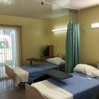 A view of a hospital patient room with two beds separated by a curtain.