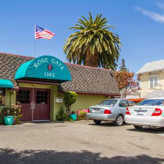 Front view of a cozy roadside motel with parked cars and an American flag.