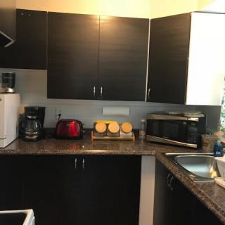 A modern kitchen with dark cabinets and various appliances.