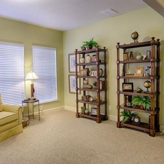 A cozy living room with bookshelves, a chair, and a lamp by the window.