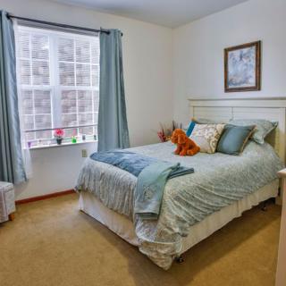 A cozy bedroom with a neatly made bed, pillows, and a window with curtains.